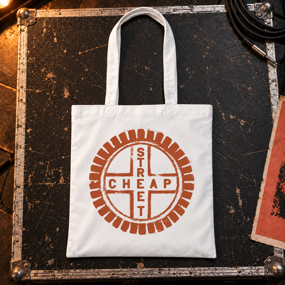 Cheap Street logo tote bag in white with a large terracotta Cheap Street emblem on the front, laid on a flight case