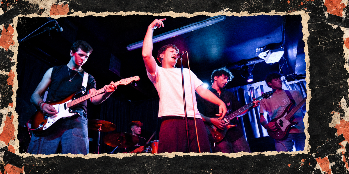 Cheap Street performing on stage, framed by torn paper: the singer in a white T-shirt points upward at the microphone, with guitarists on either side and the drummer behind