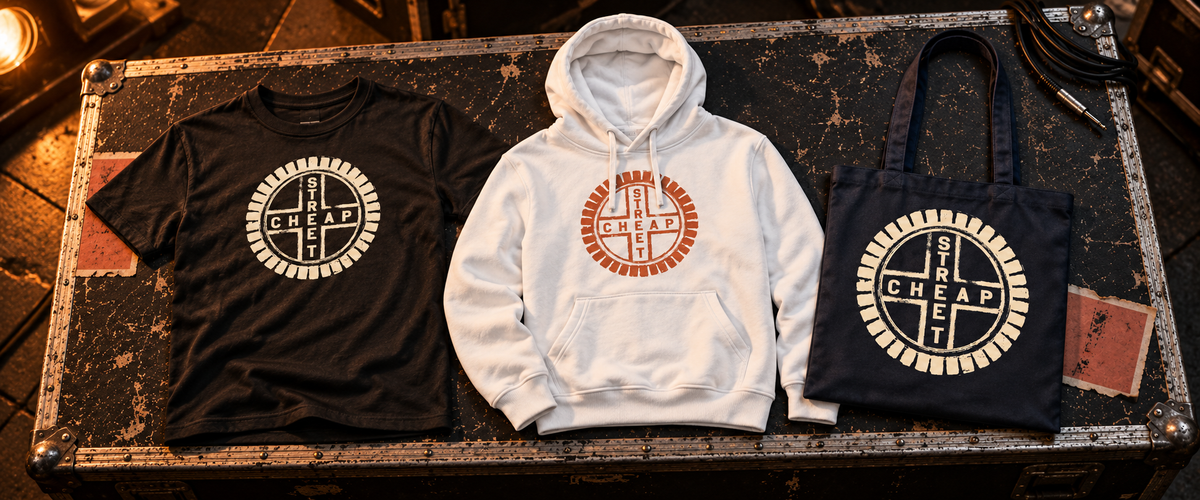 Cheap Street merch laid out on a flight case: a black T-shirt with the cream emblem, a white hoodie with the terracotta emblem and a dark tote bag with the cream emblem