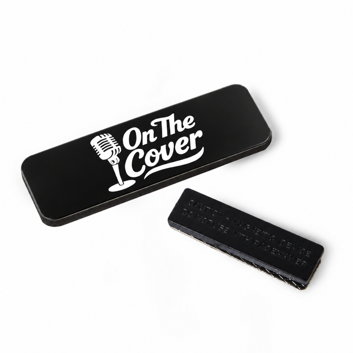 Black rectangular On The Cover badge with the white microphone logo, shown beside its magnetic back