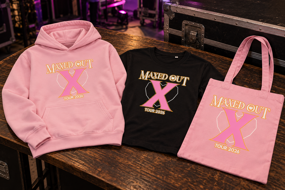 A pink hoodie, a black T-shirt and a pink tote bag, each printed with the Maxed Out X Tour 2026 artwork, laid out on a wooden table