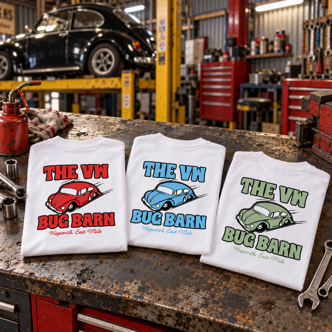 Three folded white Bug Barn T-shirts on a workbench, printed in red, blue and green